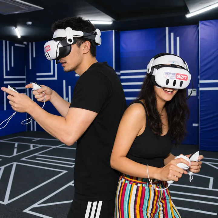 Two players stand back-to-back with VR headsets and controllers at Another World Da Nang.