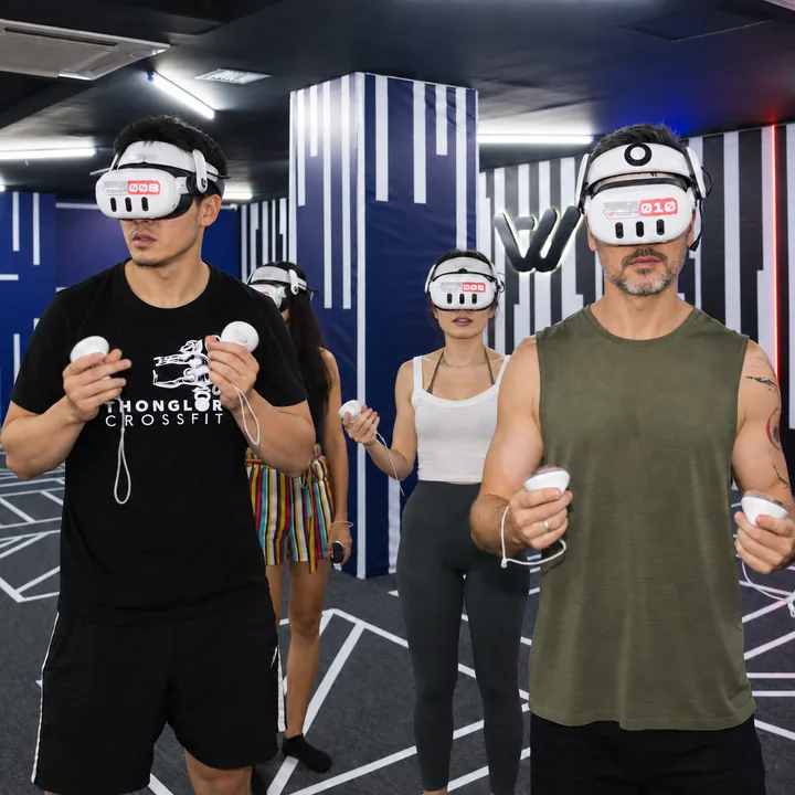 Four players hold VR controllers in front of the striped arena walls at Another World Da Nang.