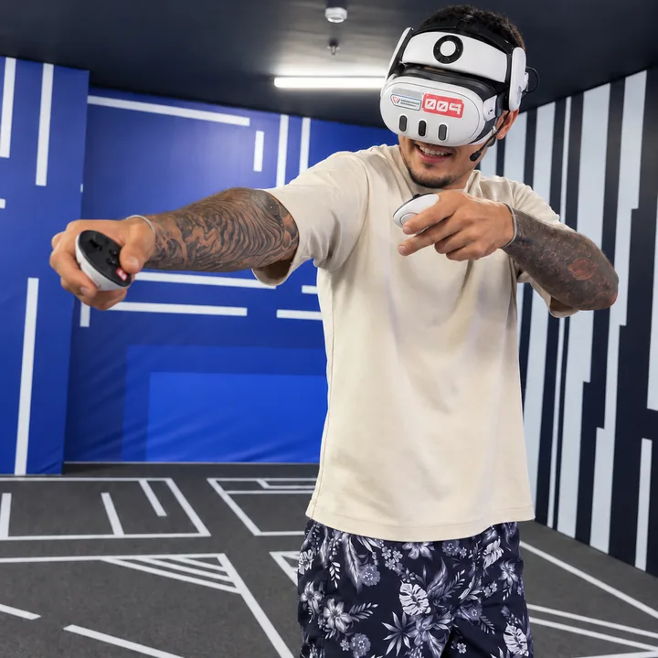 A smiling player in a light T-shirt reaches forward with a VR controller at Another World Da Nang.