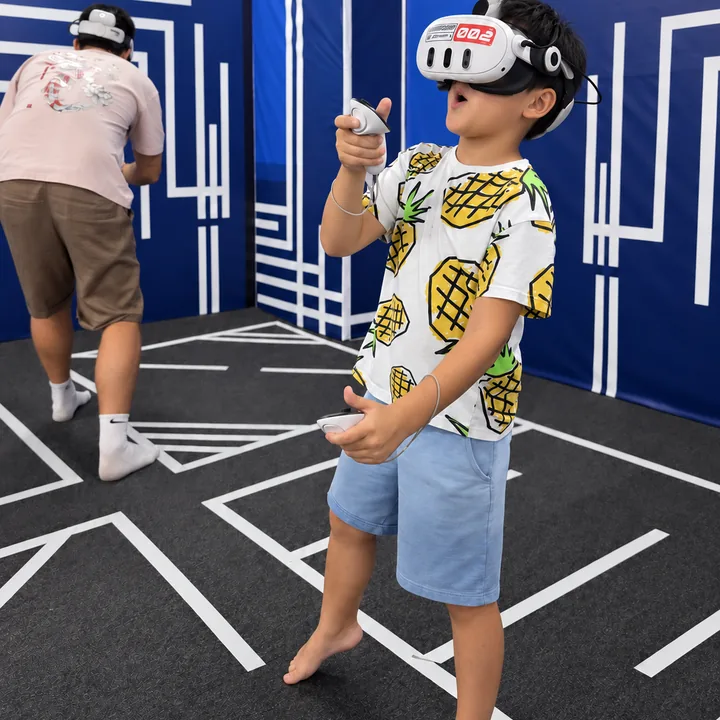 A child in a pineapple-print T-shirt raises a VR controller at Another World Da Nang.